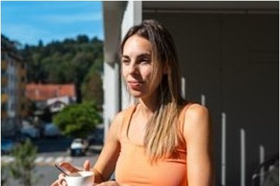 Young woman with a coffee cup enjoying the city view from her balcony