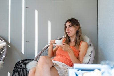 Young woman with a coffee cup on a sunny balcony